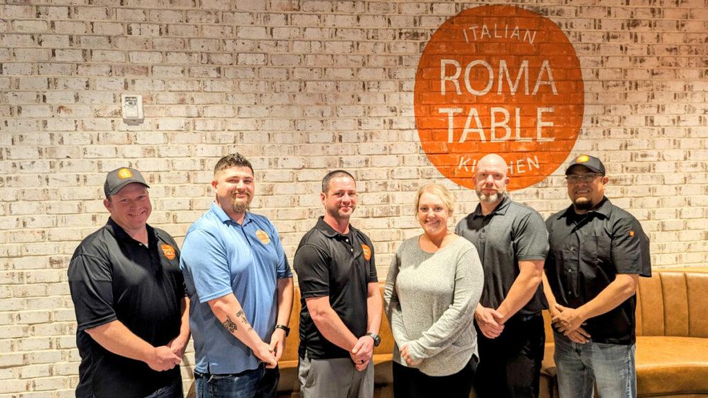 Roma Table team in front of brick wall